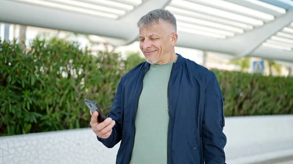 中年白发男子在公园用智能手机自信地微笑 — 图库照片