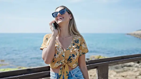 年轻的金发女游客在海滨用智能手机自信地微笑 — 图库照片