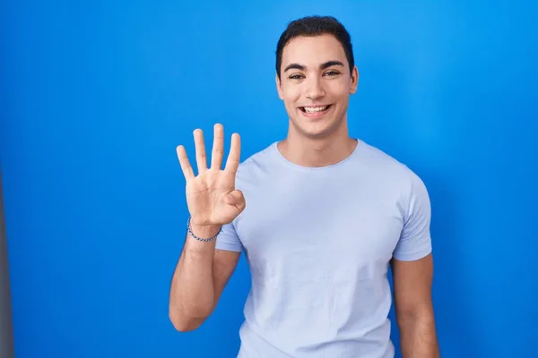 年轻的他的惊慌失措的男人站在蓝色的背景上 带着自信和快乐的微笑 用第四指尖 — 图库照片