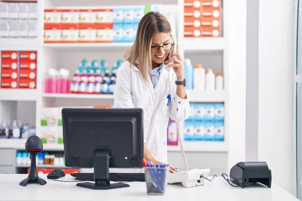 Young Beautiful Hispanic Woman Pharmacist Talking Telephone Using Computer Pharmacy — Stok fotoğraf