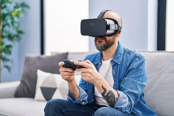 年轻的秃头男子在家里用虚拟现实眼镜玩电子游戏 — 图库照片