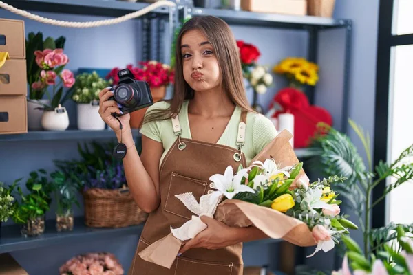 Mulher Morena Jovem Trabalhando Florista Loja Segurando Câmera Soprando Bochechas — Fotografia de Stock