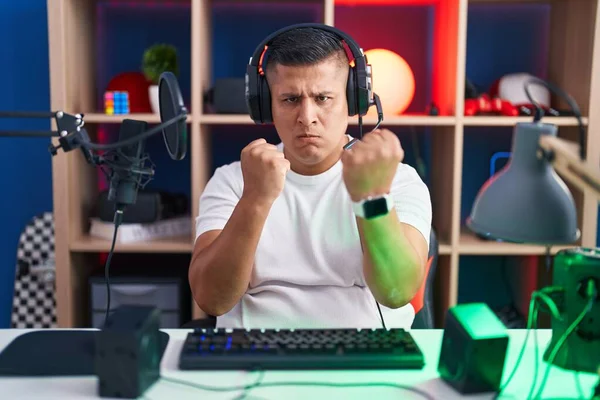 若いヒスパニック系の男ビデオゲームをプレイしている最初の防衛ジェスチャー 怒りと動揺の顔で戦う準備ができて 問題を恐れて — ストック写真