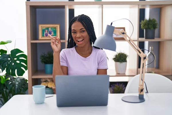 Afroamerykanka Warkoczami Używająca Laptopa Domu Uśmiechnięta Wskazówkami Boku — Zdjęcie stockowe
