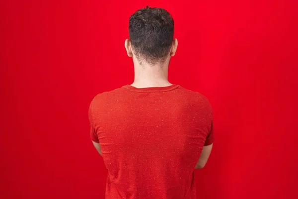Νεαρός Ισπανόφωνος Στέκεται Πάνω Από Κόκκινο Φόντο Στέκεται Πίσω Κοιτάζοντας — Φωτογραφία Αρχείου