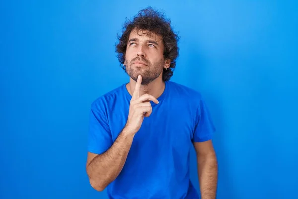 Ισπανόφωνος Νεαρός Που Στέκεται Πάνω Από Μπλε Φόντο Σκέφτεται Επικεντρώθηκε — Φωτογραφία Αρχείου