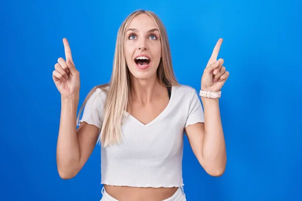 Young Caucasian Woman Standing Blue Background Smiling Amazed Surprised Pointing — 图库照片