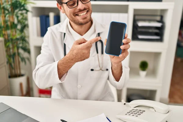 Pemuda Hispanik Pria Mengenakan Seragam Dokter Telemedicine Menunjukkan Smartphone Klinik — Stok Foto