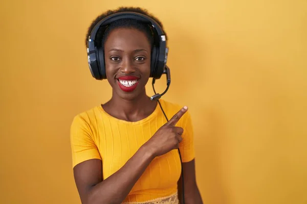 Afrikaanse Vrouw Met Krullend Haar Staande Gele Achtergrond Dragen Hoofdtelefoon — Stockfoto