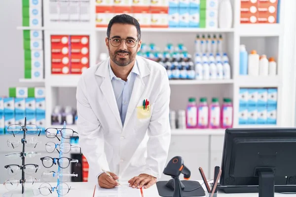 Jovem Homem Hispânico Farmacêutico Sorrindo Escrita Confiante Documento Farmácia — Fotografia de Stock