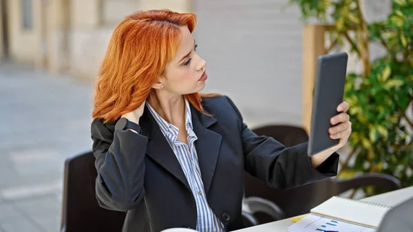 咖啡店露台前 红头发的年轻女商人正在梳理头发 看屏幕触摸板 — 图库照片