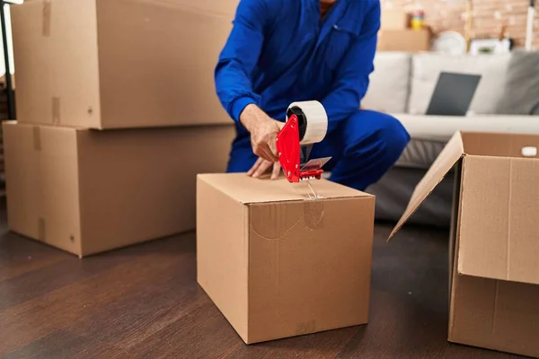 Young hispanic man worker packing package at new home