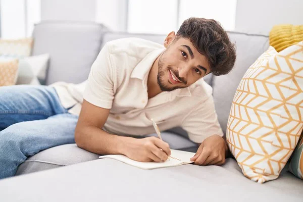Hombre Árabe Joven Escribiendo Cuaderno Sentado Sofá Casa —  Fotos de Stock