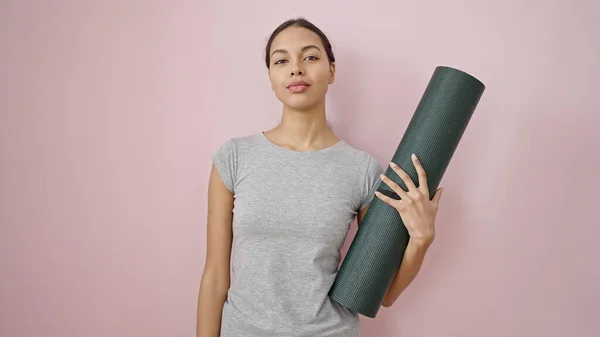 Junge Schöne Hispanische Frau Sportbekleidung Hält Yogamatte Über Isoliertem Rosa — Stockfoto