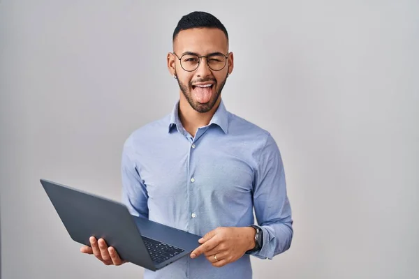 Молодой Латиноамериканец Работающий Ноутбуком Торчащим Языком Довольный Смешным Выражением Лица — стоковое фото