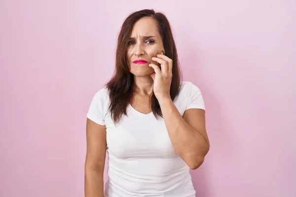 歯痛や歯の病気のために痛みを伴う式で手で口に触れるピンクの背景に立っている中世のブルネットの女性 歯科医 — ストック写真
