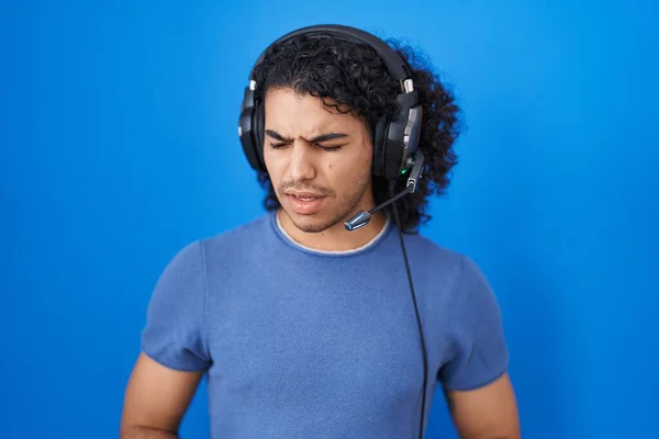 곱슬머리 스페인 남자는 스러운 때문에 헤드폰 사용하여 음악을 듣는다 — 스톡 사진