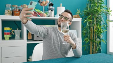 İspanyol adam masada oturmuş şarap içiyor. Yemek odasında selfie çekiyor.