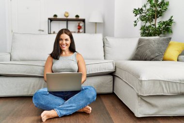 Evde dizüstü bilgisayar kullanan genç, güzel İspanyol kadın.