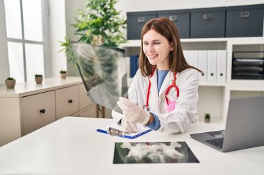Genç sarışın doktor. Klinikte sağlık raporu yazıyor.