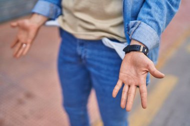 Young hispanic man showing empty pockets at street