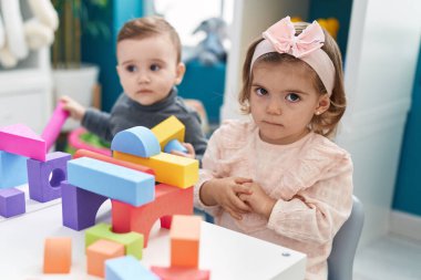 Anaokulundaki masada oturan sevimli kız ve oğlan inşaat bloklarıyla oynuyorlar.