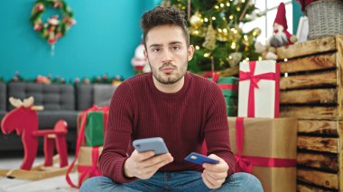 Genç İspanyol adam Noel 'i evde akıllı telefon ve kredi kartıyla kutluyor.