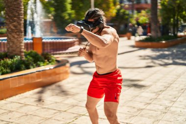 Young man using virtual reality glasses boxing at park