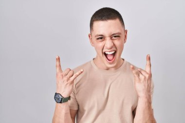 Young man standing over isolated background shouting with crazy expression doing rock symbol with hands up. music star. heavy music concept. 
