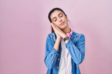 Genç, güzel bir kadın pembe arka planda ayakta uyur. Yorgun düşler kurar, ellerle poz verir ve gözleri kapalı gülümserdi.. 