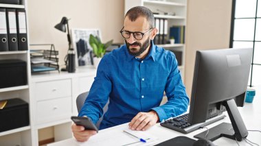 Ofiste bilgisayar ve akıllı telefon kullanan İspanyol bir iş adamı.