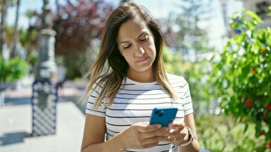 Ortadoğulu kadın parkta akıllı telefon kullanıyor.