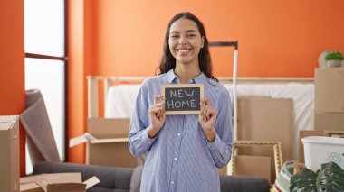 Genç ve güzel İspanyol kadın gülümsüyor. Yeni evinde kendine güvenen bir karatahta tutuyor.