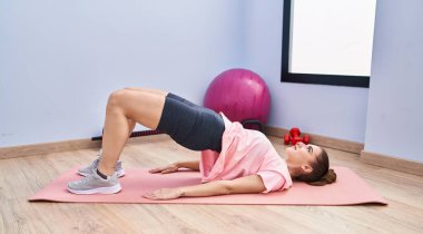 Spor merkezinde karın kaslarını çalıştıran genç bir kadın.