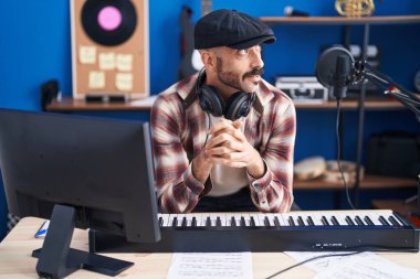 Young hispanic man musician smiling confident at music studio