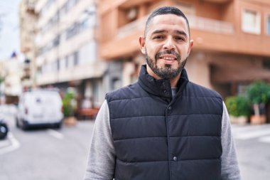 Young latin man smiling confident standing at street