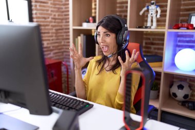 Orta yaşlı İspanyol kadın video oyunları oynuyor kulaklıkla başarıyı kutluyor kollarını kaldırıyor ve gözleri kapalı heyecanla bağırıyor. Kazanan konsept 