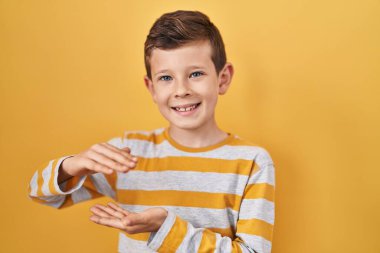 Sarı arka planda duran genç beyaz çocuk. Ellerinde büyük ve büyük bir işaret var. Ölçü sembolü. Kameraya bakıp gülümsüyor. ölçüm kavramı. 