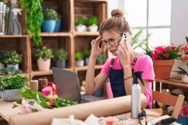 Çiçekçide bilgisayarla konuşan sarışın bir çiçekçi.