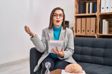 Orta yaşlı kadın psikolog, psikoloji merkezinde kendinden emin bir şekilde gülümsüyor.