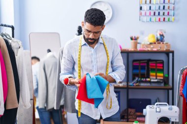 Young arab man tailor holding cloths at tailor shop
