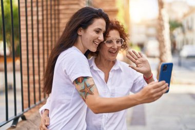 İki kadın anne ve kız birbirlerine sarılıyorlar ve sokakta video görüşmesi yapıyorlar.