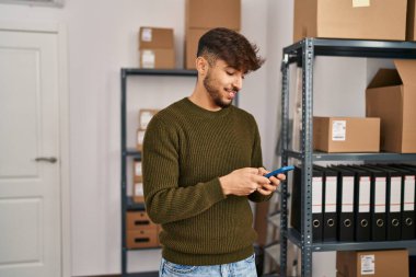 Young arab man ecommerce business worker using smartphone at office