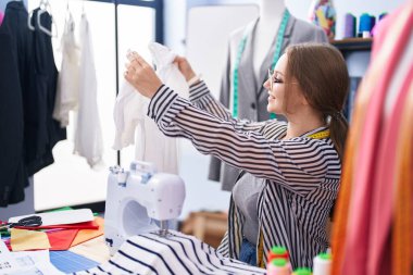 Terzi dükkanında kendine güvenen, sırıtan genç sarışın kadın.