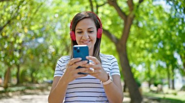 Ortadoğulu kadın parkta kulaklık takıyor.