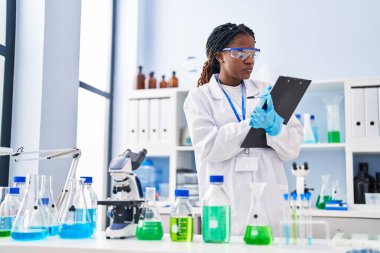 African american woman scientist writing report working at laboratory