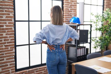 Young beautiful hispanic woman business worker looking throw the window at office