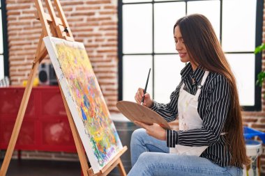 Sanat stüdyosunda kendine güvenen güzel İspanyol kadın sanatçı gülümsüyor.