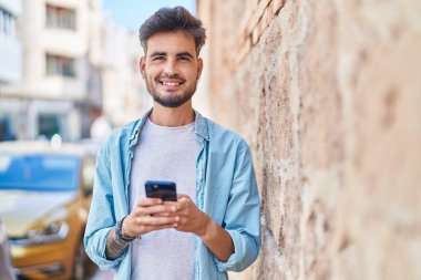 Sokakta akıllı telefon kullanan, kendine güvenen genç bir İspanyol.