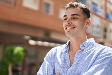 Young hispanic man smiling confident looking to the side at street